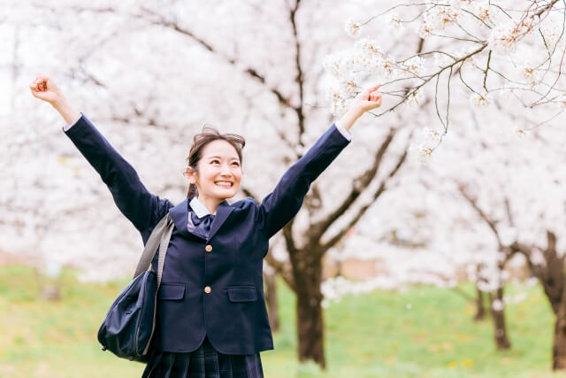 サクラの木の下で万歳する女子中学生